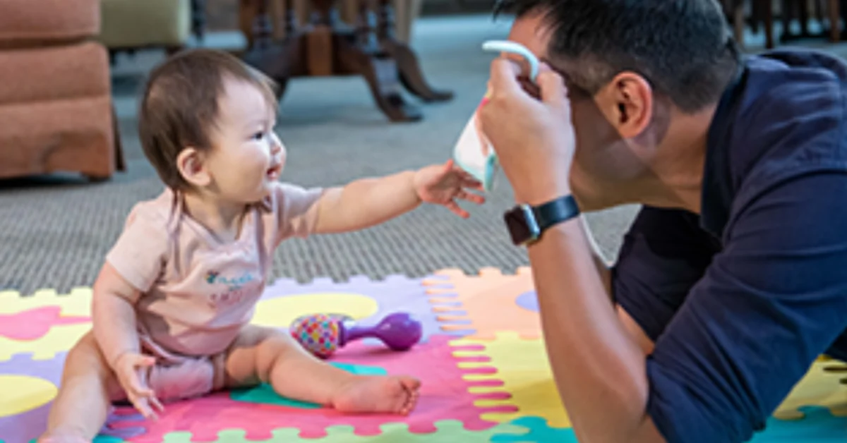 Un père jouant à coucou-caché avec son bébé