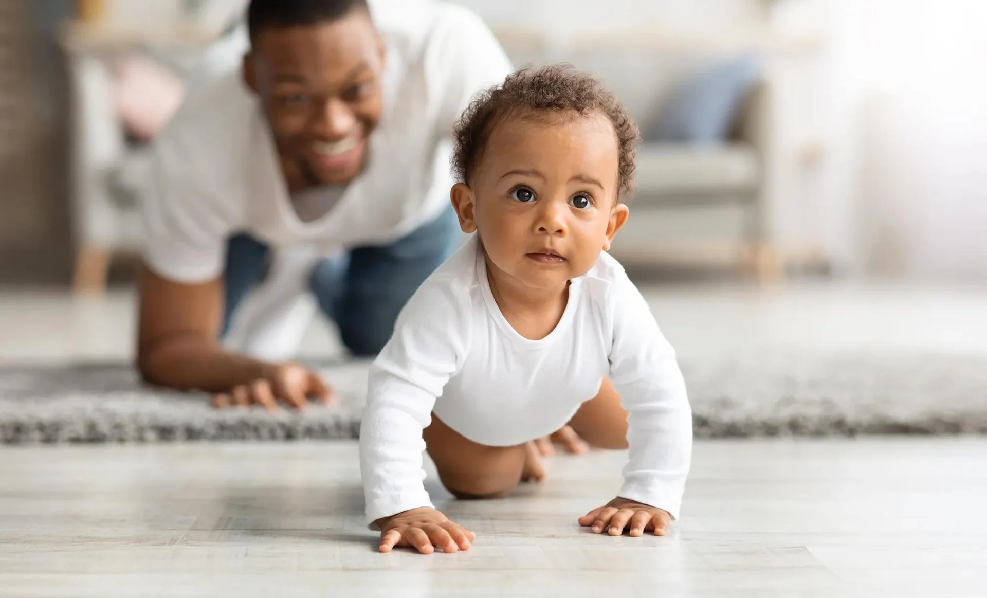 Bébé souriant qui rampe à quatre pattes sur le sol
