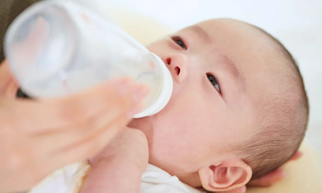 Bébé buvant un soluté de réhydratation orale au biberon pour soigner une gastro.