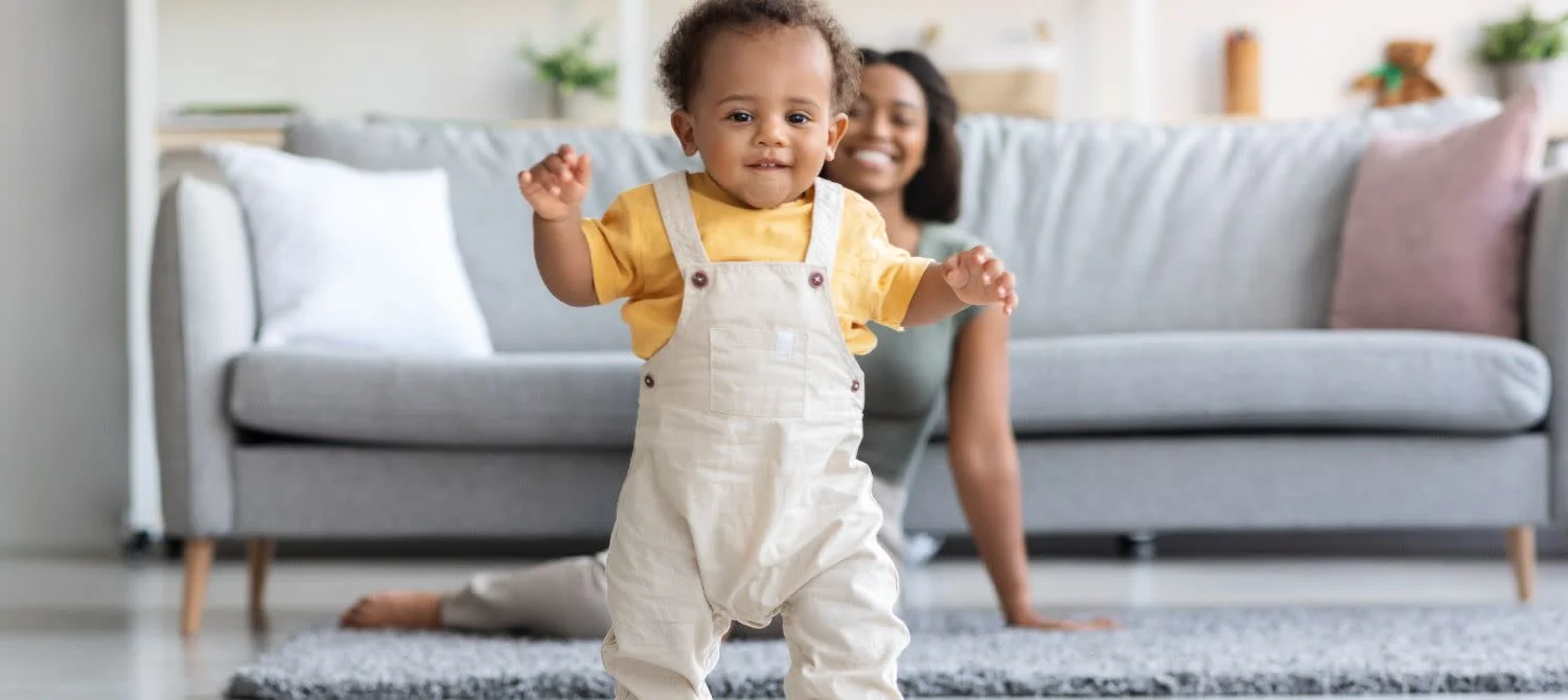 Bébé de 12 mois faisant ses premiers pas avec assurance dans le salon
