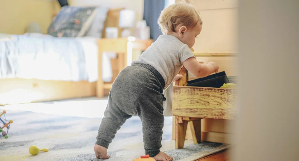 Bébé de 9 mois se hissant debout en s'agrippant à un meuble de salon