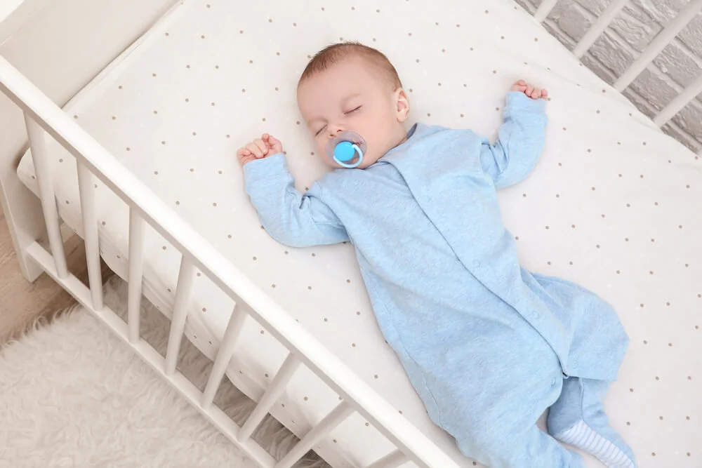 Bébé dormant en toute sécurité sur le dos dans son berceau pour prévenir le reflux la nuit