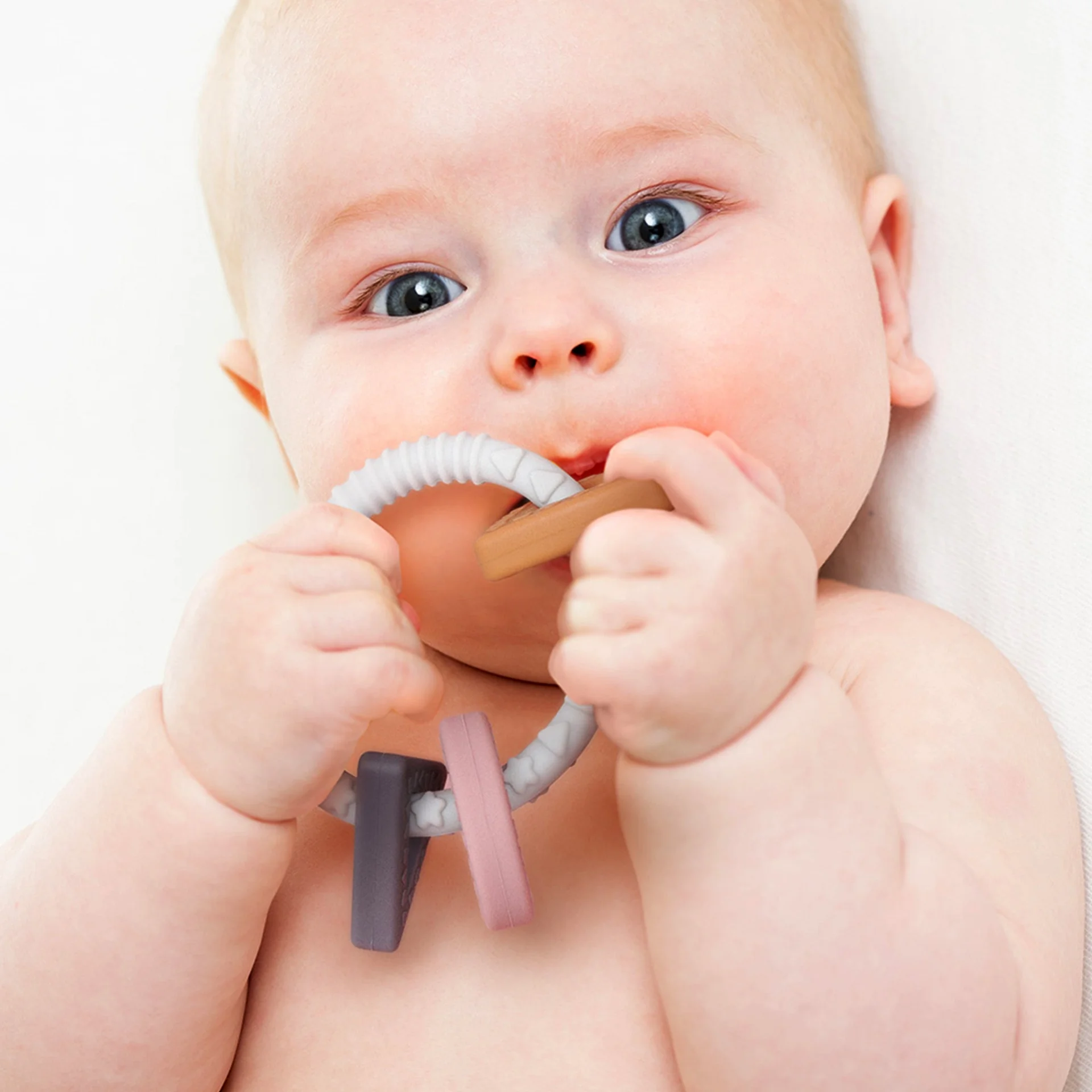 Bébé mordillant un anneau de dentition pour soulager une poussée dentaire.