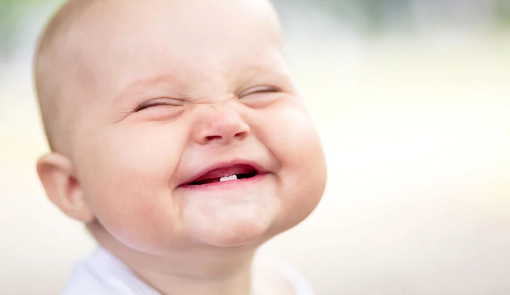 Bébé souriant montrant ses deux premières dents de lait inférieures