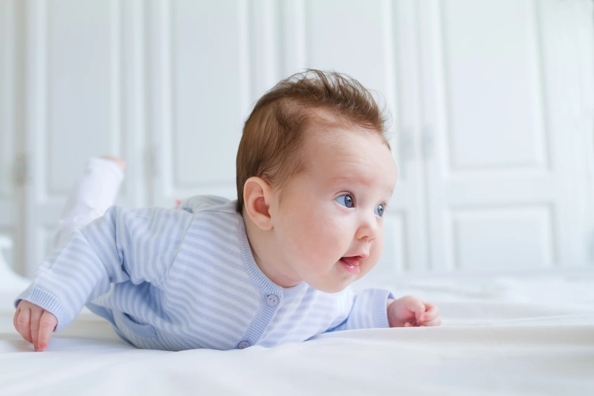 Développement bébé 3 mois : nourrisson soulevant sa tête et son torse sur le ventre