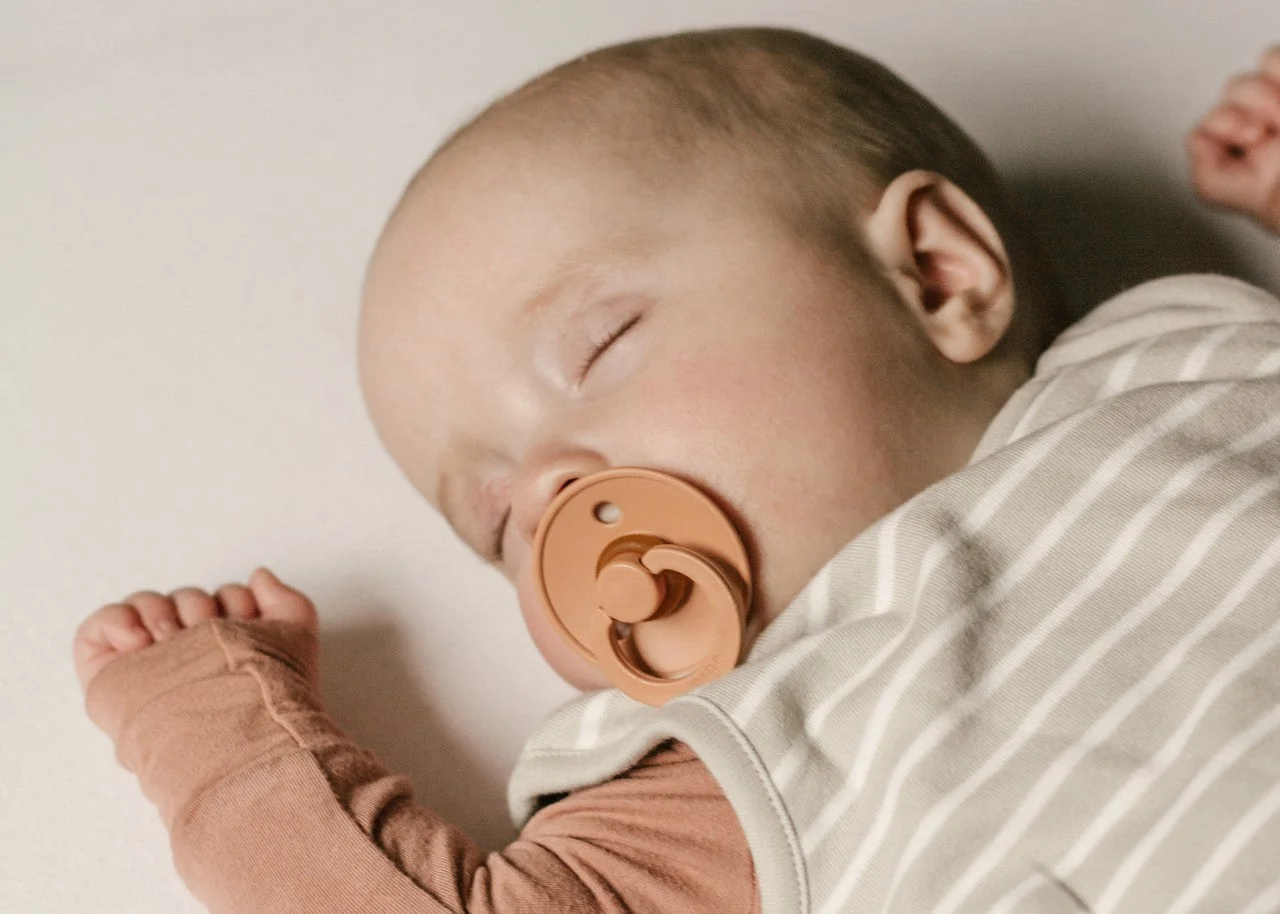 Gros plan d'un bébé endormi avec une sucette, un facteur protecteur reconnu.