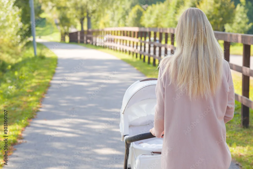 Maman marchant avec sa poussette dans un parc, étape clé de la reprise sport après accouchement.