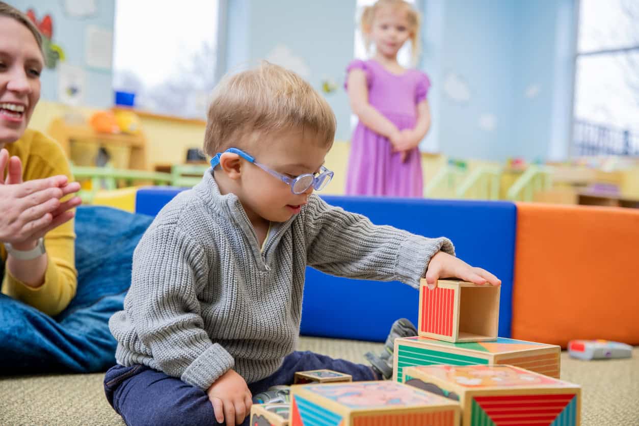 Jeune garçon avec lunettes construisant une tour de blocs