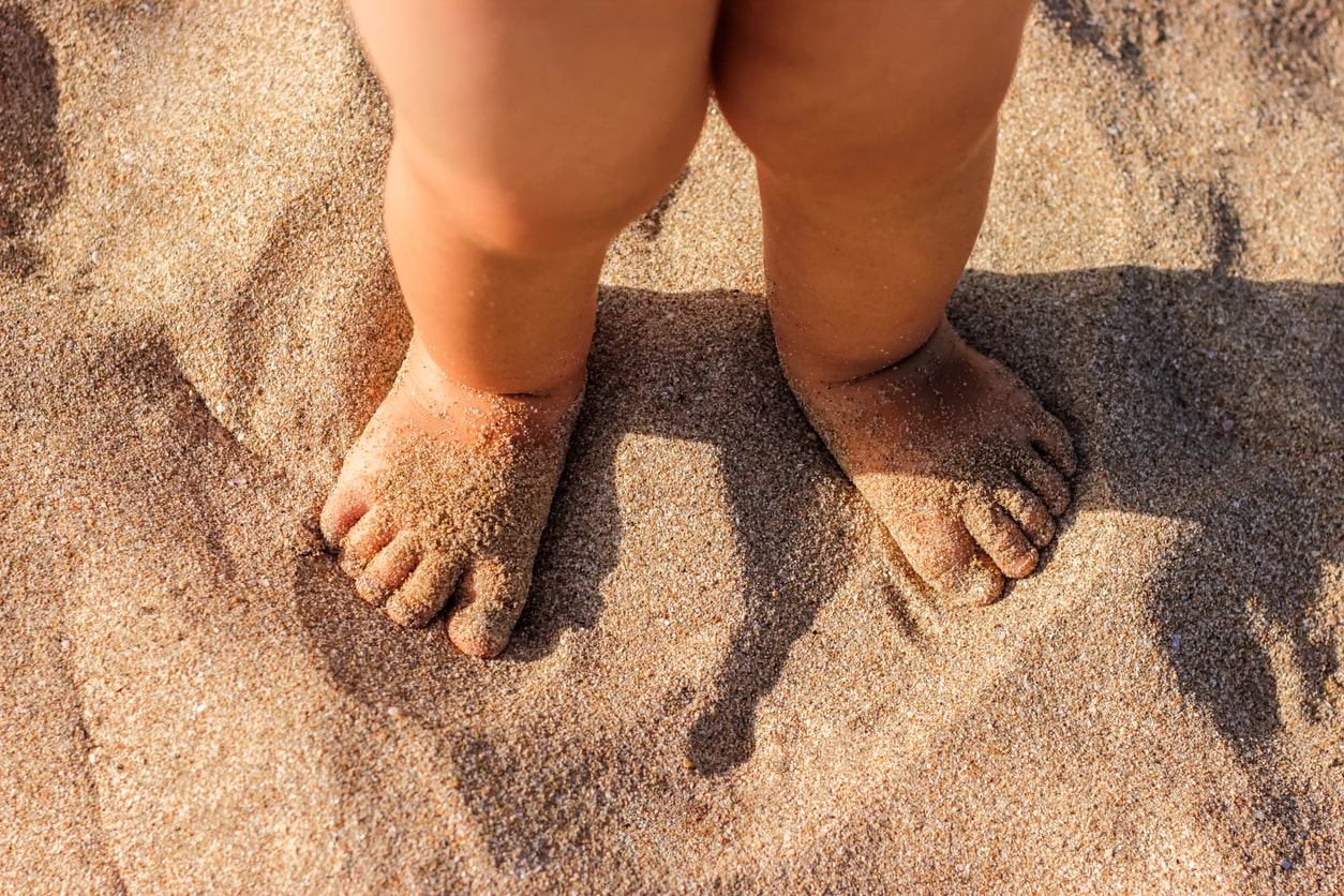 Petits pieds de bébé sur le sable chaud