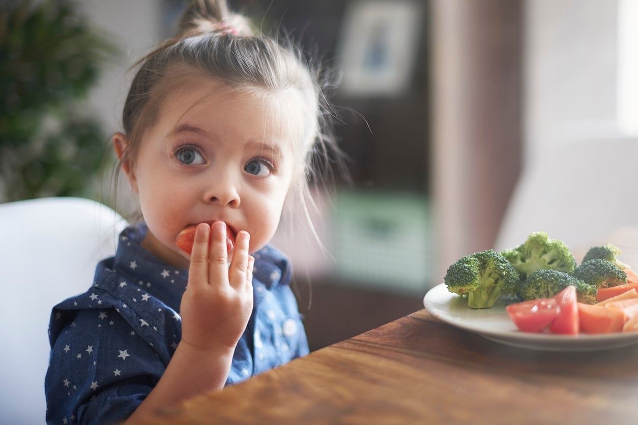 Petite fille mangeant des légumes avec plaisir