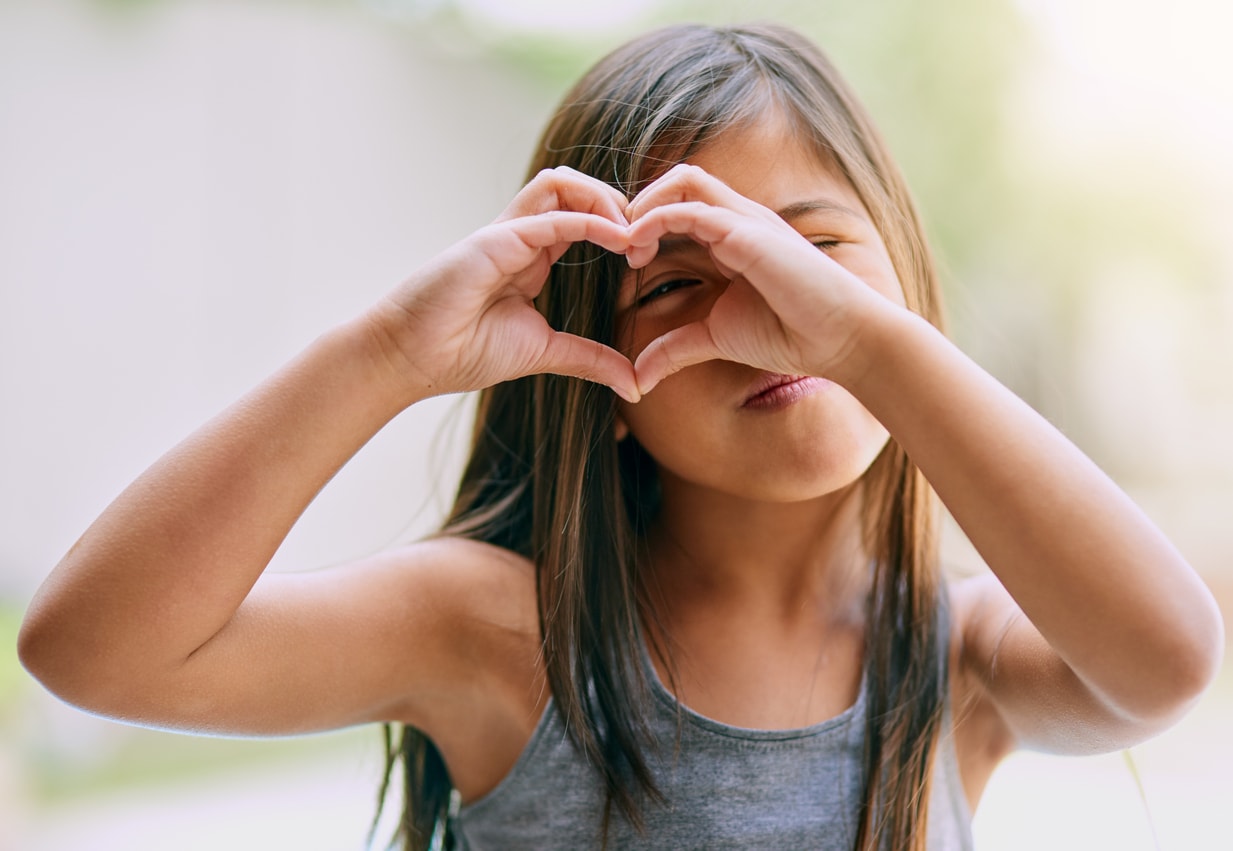 Petite fille faisant un cœur avec ses mains