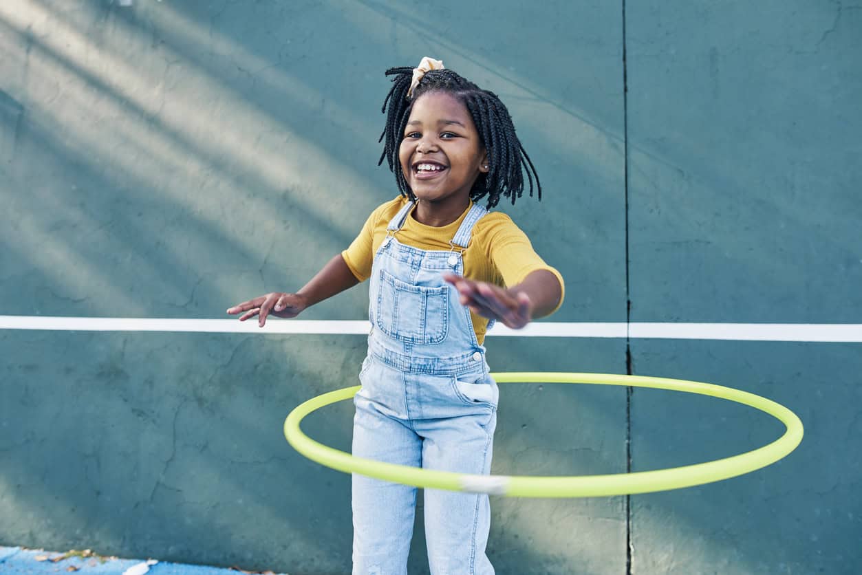 Petite fille souriante jouant avec un cerceau jaune