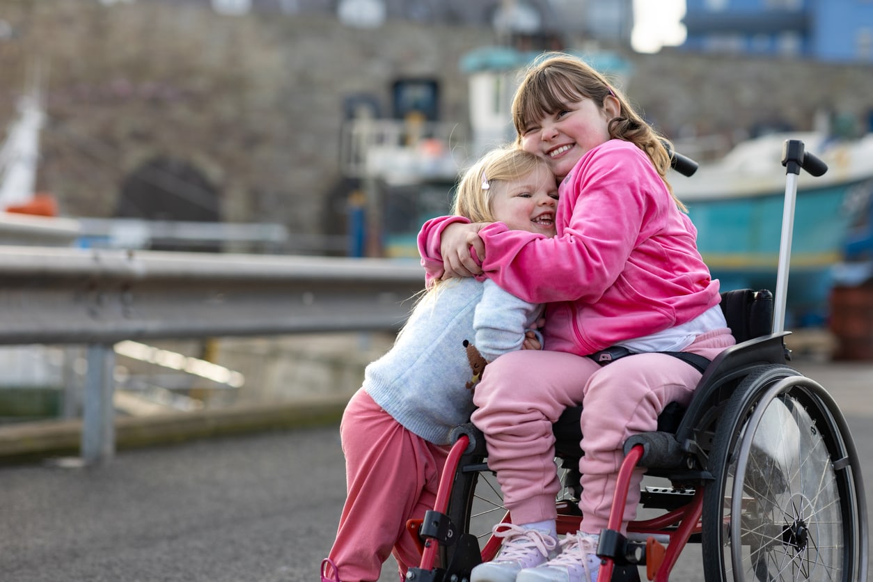 Deux sœurs souriantes, l'une en fauteuil roulant