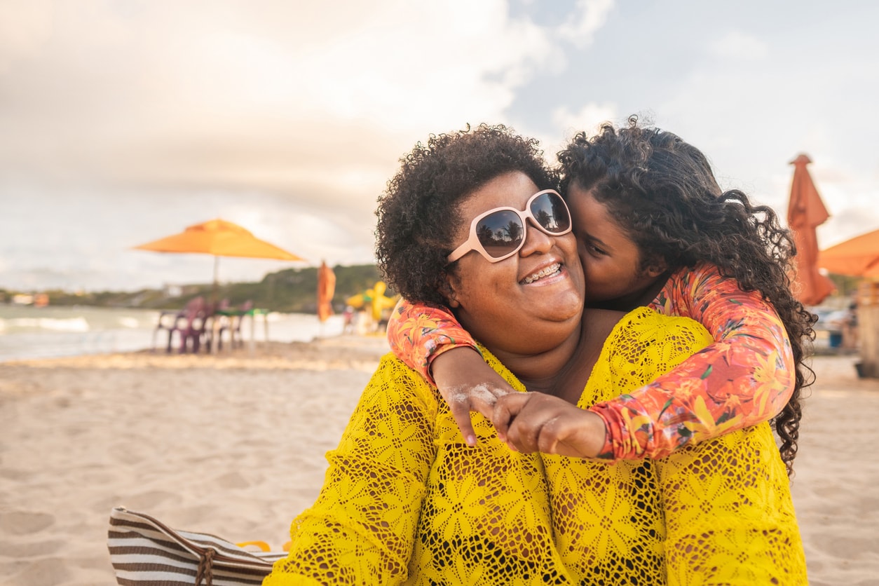 Petite fille embrassant sa maman sur la plage