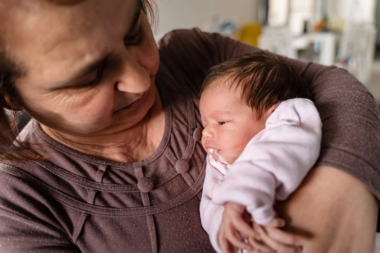 Bébé régurgitant dans les bras de sa grand-mère