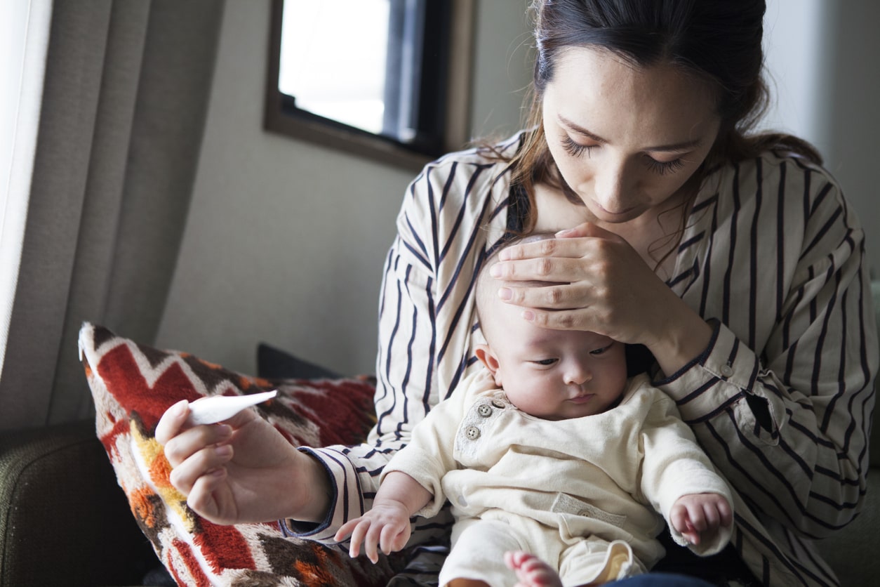 Maman prenant la température de son bébé sur ses genoux