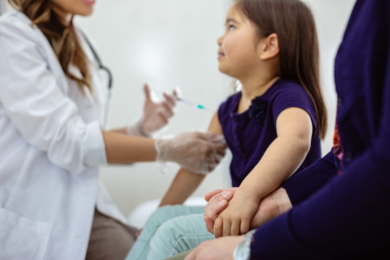 Enfant tenant la main de sa maman pendant un vaccin