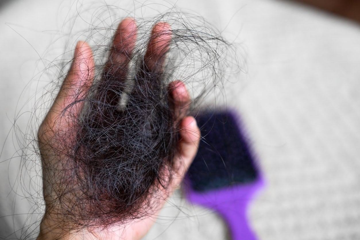 Jeune maman observant ses cheveux qui tombent