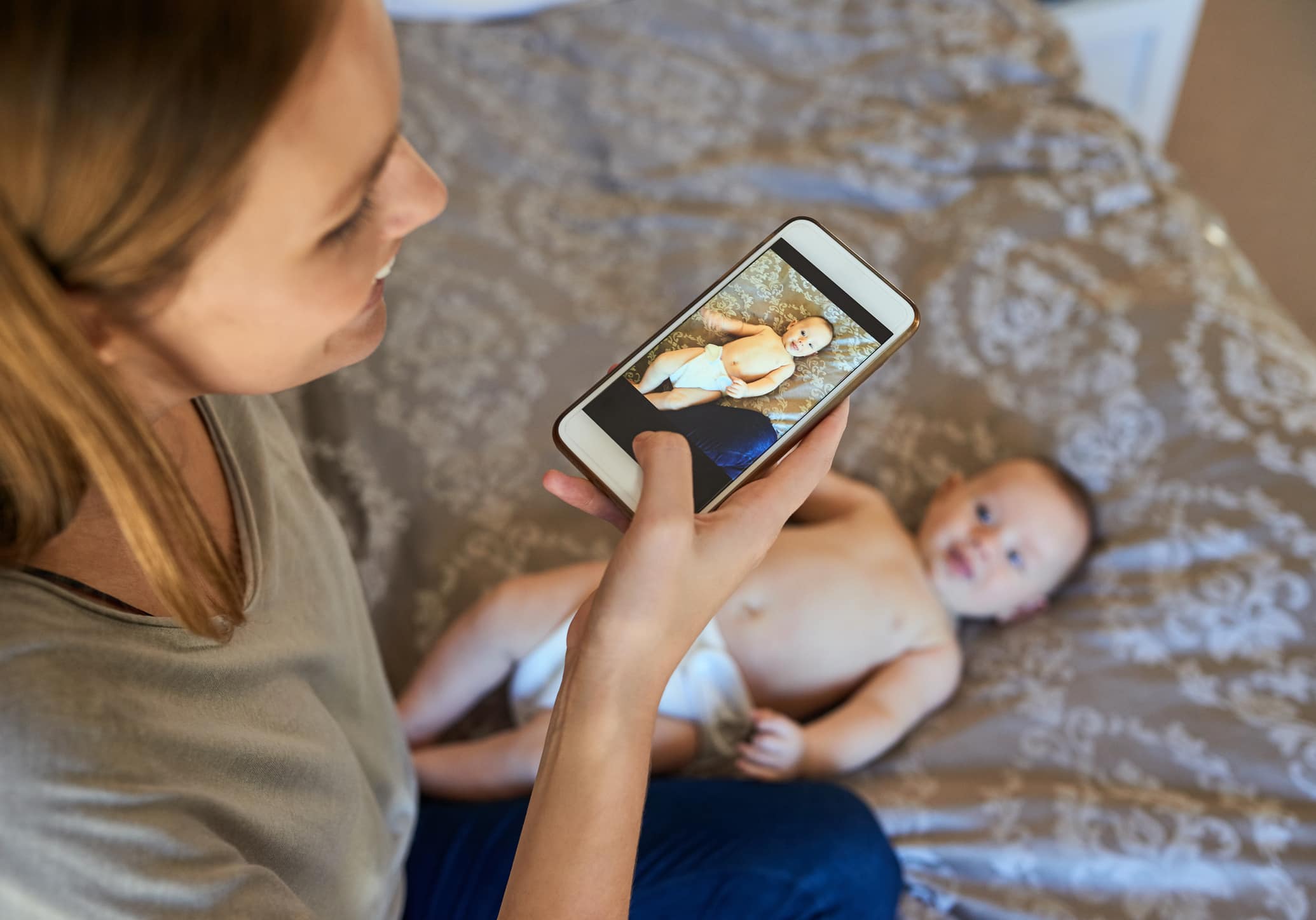Une jeune mère photographiant son bébé à la maison