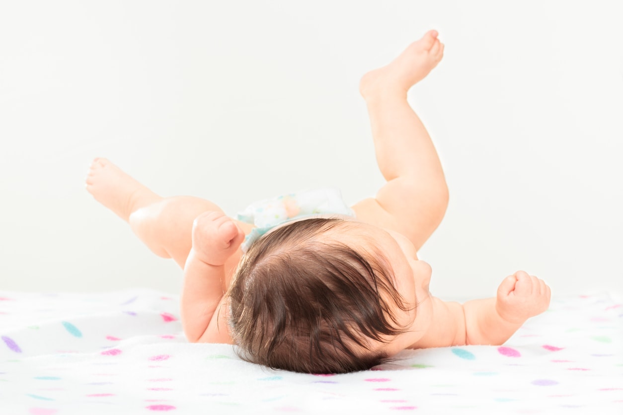 Bébé fille allongée sur une couverture à pois levant les jambes