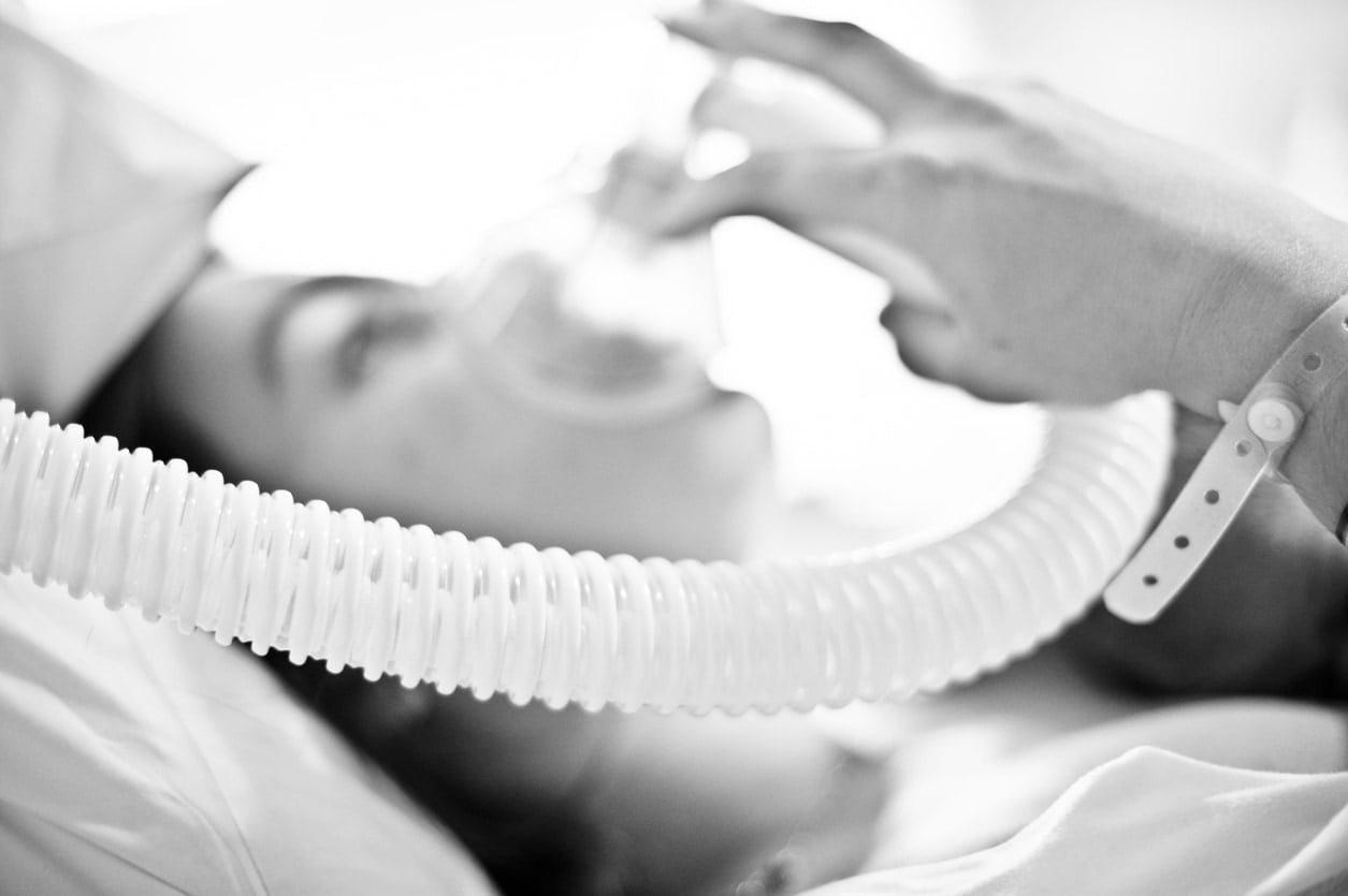 Future mère allongée sur un lit d'hôpital, utilisant un masque de protoxyde d'azote pendant le travail