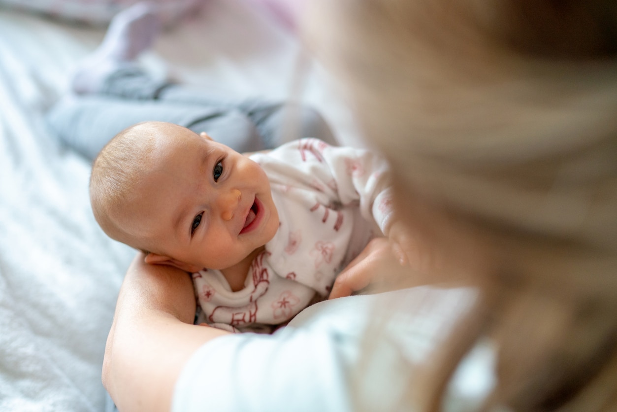 Mère portant son bébé qui sourit à la maison