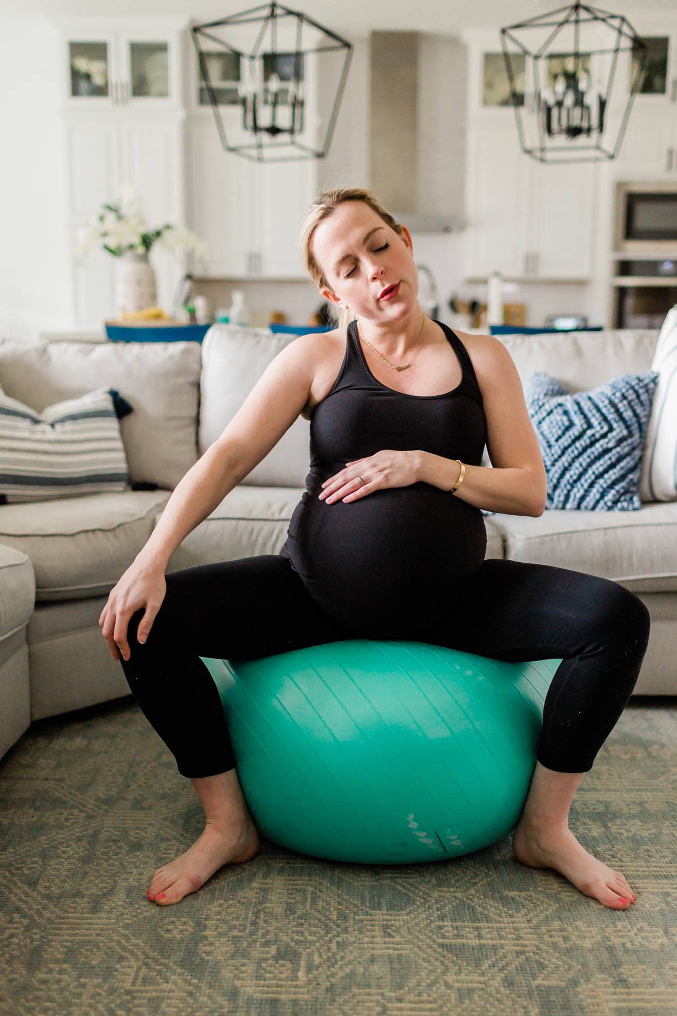 Femme enceinte assise sur un ballon de grossesse dans son salon