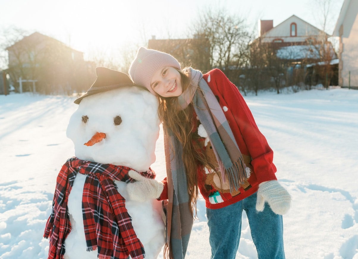 Fille avec un bonhomme de neige lors d'une journée ensoleillée