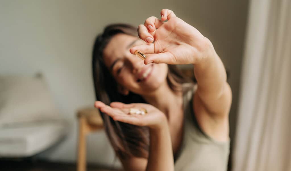 Femme souriante tenant une capsule de vitamine