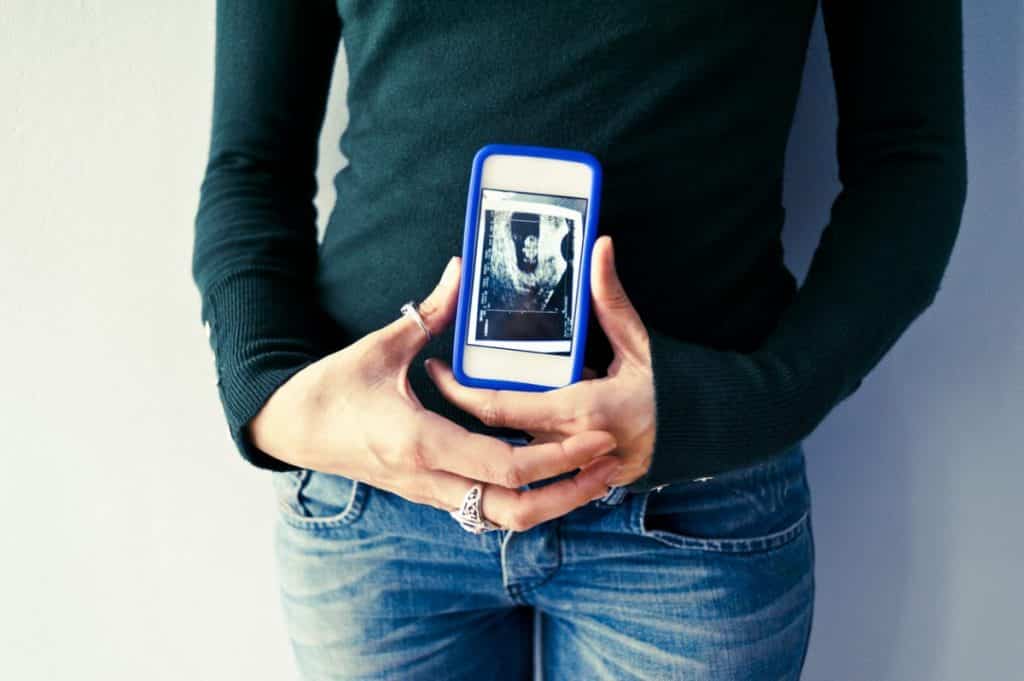 Une femme enceinte regardant une échographie sur son smartphone