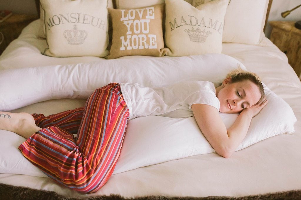 Femme enceinte dormant sur le côté avec un coussin de maternité