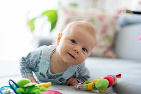Bébé éveillé sur le ventre avec des jouets.