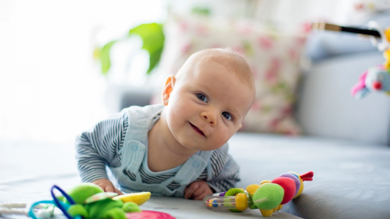 Bébé éveillé sur le ventre avec des jouets.